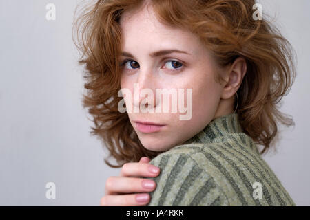Beautiful red-haired girl with long curly hair gently looking at the camera Stock Photo