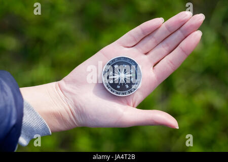 Hand holding the black compass isolated on green background Stock Photo