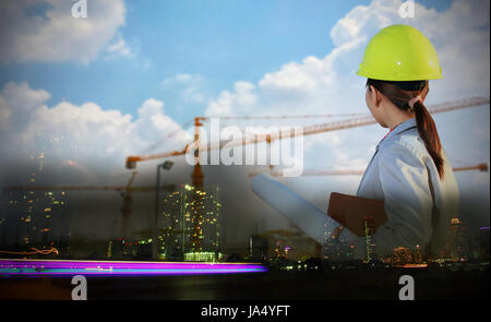 Double exposure portrait women asia engineer working and holding blueprints at construction site Stock Photo