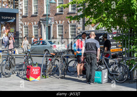 Food delivery riders for Deliveroo and Just Eat take a break in Cork, Ireland. Stock Photo