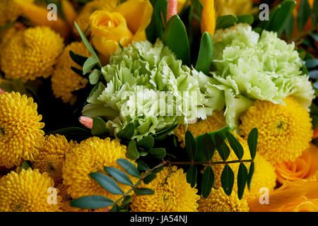 Yellow bouquet with green carnation, in the composition of chrysanthemums, roses and dyed grains Stock Photo