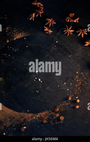 Macro image of star anise. Eastern seasoning for desserts. Trace of cocoa on a dark table top scattered star anise. The atmosphere of the kitchen Stock Photo