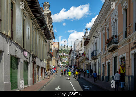 Bikers and pedestrians on a sunday closed street of Quito and Monument to the Virgin Mary on the top of El Panecillo Hi Stock Photo