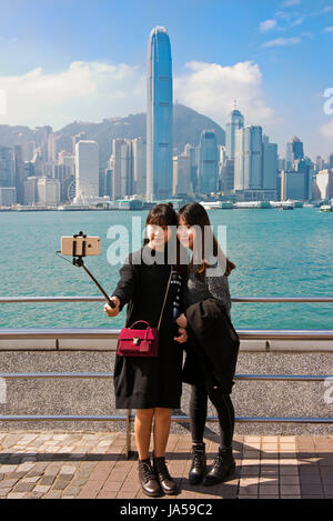 Vertical portrait of tourists taking selfies of the dramatic skyline of Hong Kong Island, China. Stock Photo