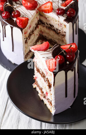 sliced mousse cake with fresh strawberry and cherry, decorated with chocolate closeup. vertical Stock Photo