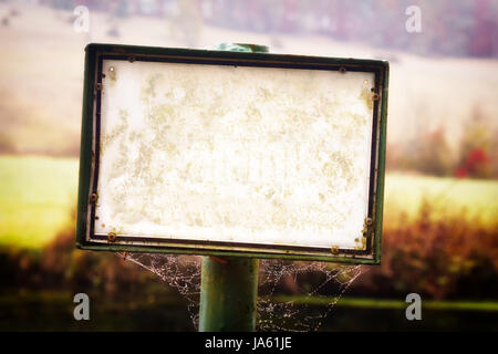 Empty, damaged white sign standing on a dirty pole with spiderweb - no text, lots of copy space. Stock Photo