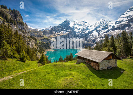 Amazing tourquise Oeschinnensee with waterfalls, wooden chalet and Swiss Alps, Berner Oberland, Switzerland. Stock Photo