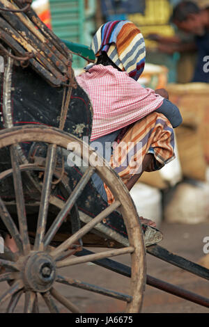 Man resting on a hand pulled rickshaw in Kolkata, West Bengal, India. Stock Photo