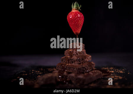 One red straberry in the air on a top of dark chocolate Stock Photo