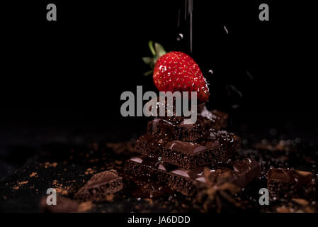 One red straberry on a dark  chocolate, crushed.Coconut chips Stock Photo