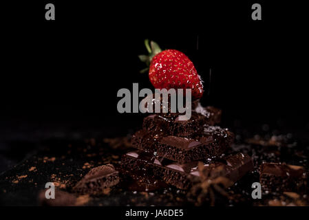 One red straberry on a dark  chocolate, crushed.Coconut chips Stock Photo