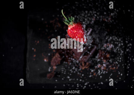 One red straberry on a dark  chocolate, crushed.Coconut chips Stock Photo