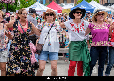 London, Ontario, Canada. 4th June, 2017. Fiesta London! Mexican festival celebrating the sounds, culture, and food of Mexico at the Covent Garden Market, in downtown London, Ontario. Held annually, the festival brings together a variety of performers, colourful folkloric dancers, singers, and entertainment from throughout Latin America. A group of women friends wearing straw hats embrace facing the camera, dancing and listening to the concert music and having a great time together. Credit: Rubens Alarcon/Alamy Live News Stock Photo