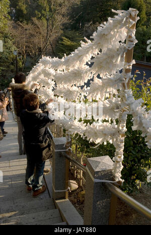 Omikuji (fortunes sold at shinto shrines) with bad luck left at Tsurugaoka Hachiman-gu Shinto shrine in Kamakura Stock Photo