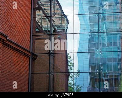 Office building, block, red brick, skyscraper made of metal and glass, sky reflections on windows, finance center, bank, business apartments Stock Photo