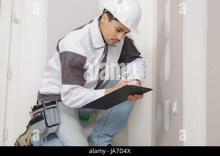 young builder writing something on site plans Stock Photo