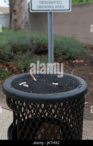 An ashtray for smokers and a designated smoking area sign outside a office building Stock Photo