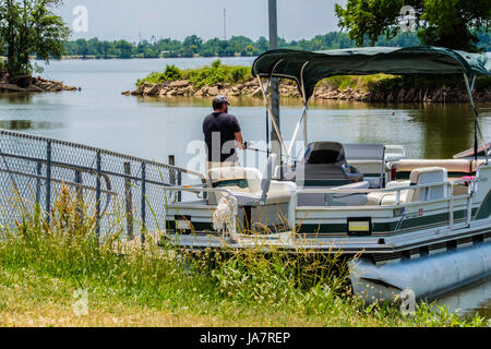 A Caucasian man in his 40s fishes from a pontoon boat on the North Canadian river near Oklahoma City, Oklahoma, USA. Stock Photo