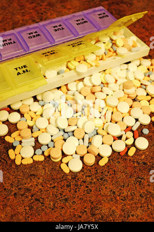 Pills spilling out of pill box onto counter. Stock Photo