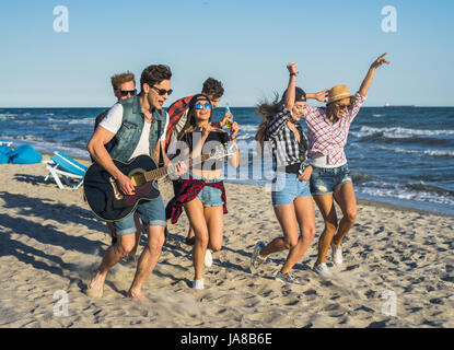 Party on the beach with guitar. Friends dancing together at the beach Stock Photo