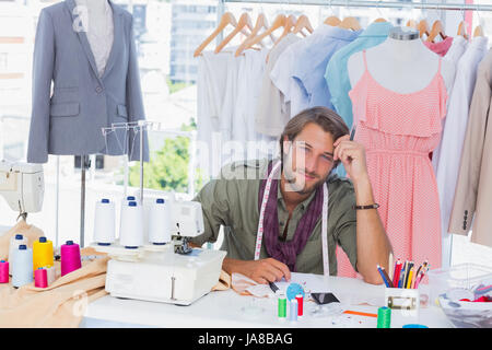 Thoughtful fashion designer sitting behind his desk Stock Photo