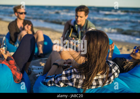 group of friends with guitar and alcohol on the beach party Stock Photo