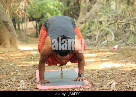 Young Indian man performing the crow pose. (Bakasana) Location - Cubbon Park, Bangalore. Stock Photo