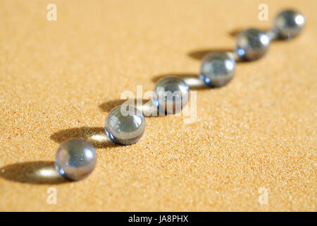 Abstract composition with few blue glass balls in a row on sand surface Stock Photo
