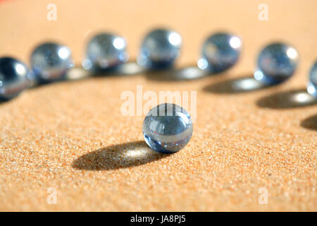Abstract composition with few blue glass balls on sand surface Stock Photo