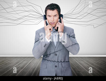 Businessman trapped by telephone wires looking at camera in empty room Stock Photo