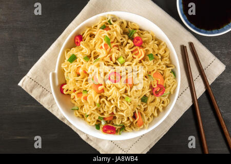 Instant noodles with vegetables, sauce, chopsticks, copy space Stock Photo