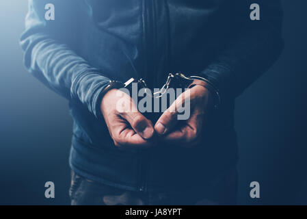 Arrested computer hacker and cyber criminal with handcuffs, close up of hands Stock Photo