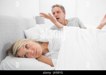 Woman refusing to listen to partner during a fight in bed at home in bedroom Stock Photo