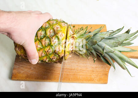 Man cutting pineapple fruit on a wooden board Stock Photo