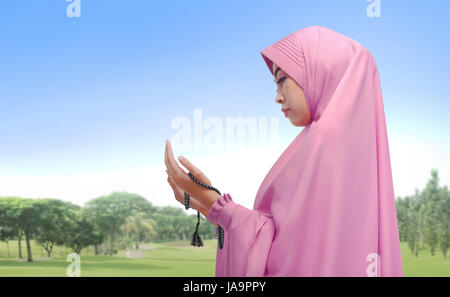 Beautiful asian muslim woman praying with prayer beads at outdoor Stock Photo