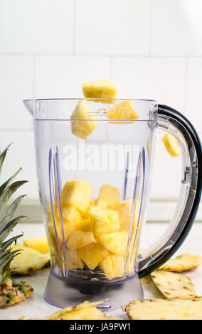 Pineapple slices falling into blender for a smoothie Stock Photo