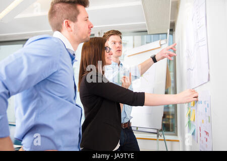 Business People Discussing Over Line Graph Stuck On Wall Stock Photo