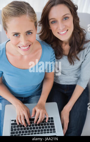 Women posing while surfing the net and sitting on the sofa Stock Photo