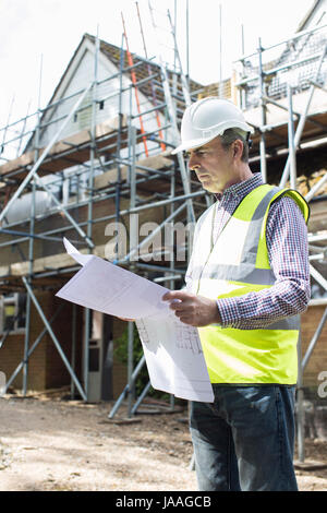Architect On Building Site Looking At House Plans Stock Photo