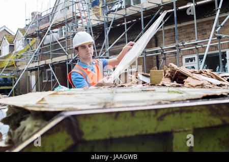 Builder On Site Putting Waste Into Rubbish Skip Stock Photo