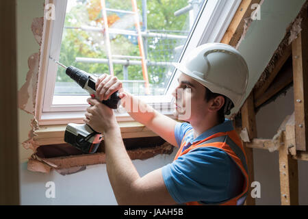 Construction Worker Using Drill To Install Replacement Window Stock Photo