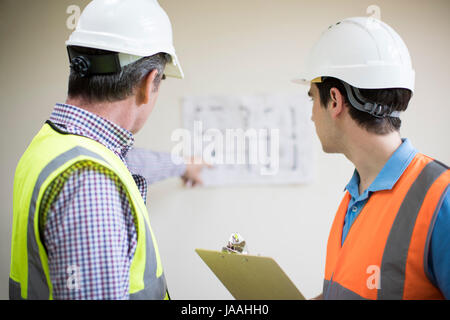 Rear View Of Architect On Site Discussing Plans With Builder Stock Photo