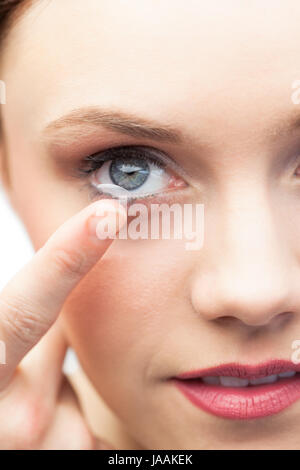 Pretty model on white background applying contact lens Stock Photo