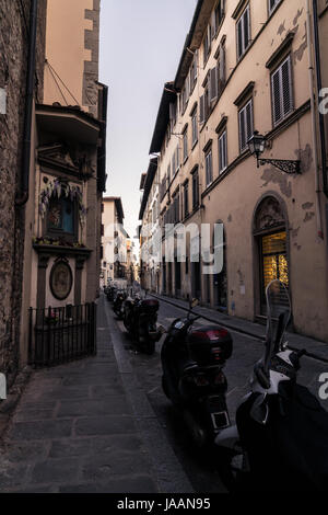 Narrow street and buildings with parked scooters in Florence Italy, at dawn. Stock Photo