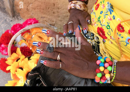 Latina woman smoking cigar in Havana, Cuba. Hispanic black lady and tobacco smoke, Caribbean folklore. Closeup of hand holding cigar with Cuban flags  Stock Photo