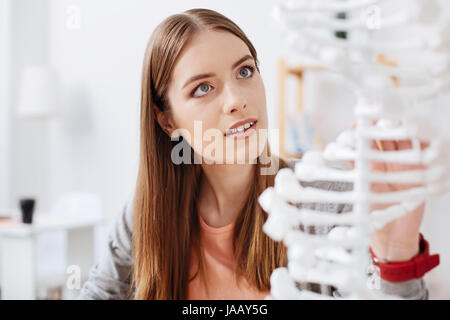 Magical mechanism. Smart charming young lady sitting in class and examining professional model while being focused on her education Stock Photo