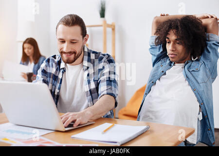 Dream team. Analytical ambitious clever guys getting ready with the assignment while one of them developing a presentation and another waiting for fri Stock Photo