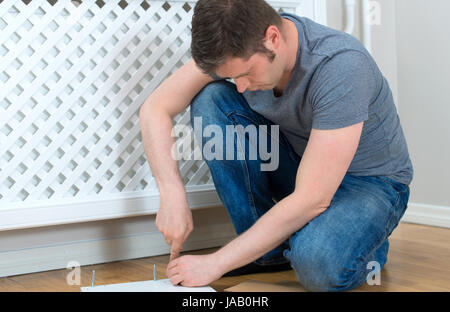 Handsome man assembling furniture at home. Stock Photo