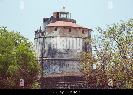 The lighthouse in Fort Aguada on the west coast of India emerging from behind the wall of the fort Stock Photo