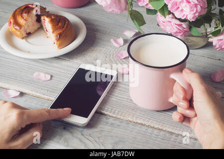 Cup of milk and a phone in hands Stock Photo